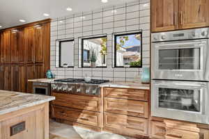 Kitchen featuring stainless steel appliances, light stone counters, wood finish cabinetry, and recessed lighting