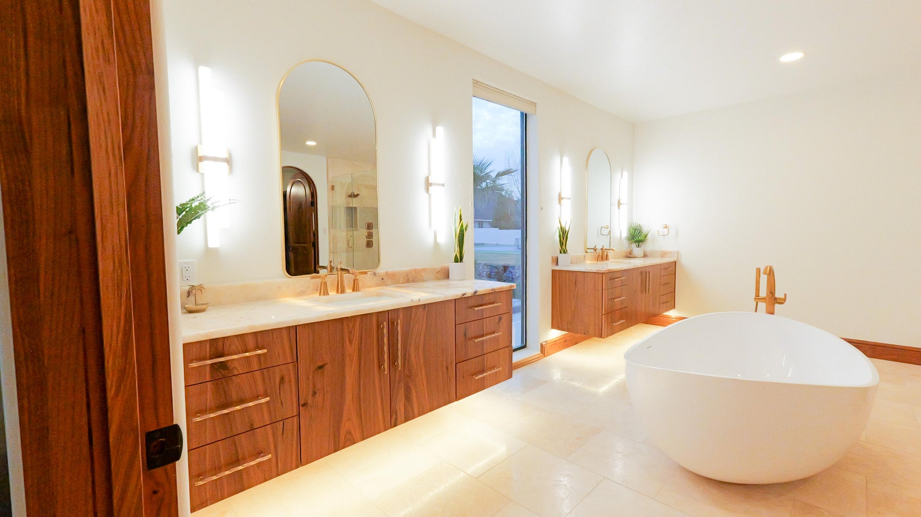 Floating cabinets with two vanities, an enclosed shower, a freestanding bath, and recessed lighting