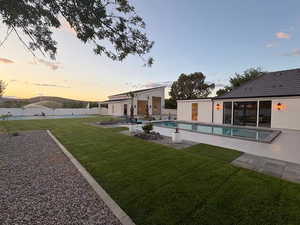 Back of house at dusk with a patio and a yard