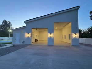 Property exterior at dusk featuring stucco siding, driveway, and a garage