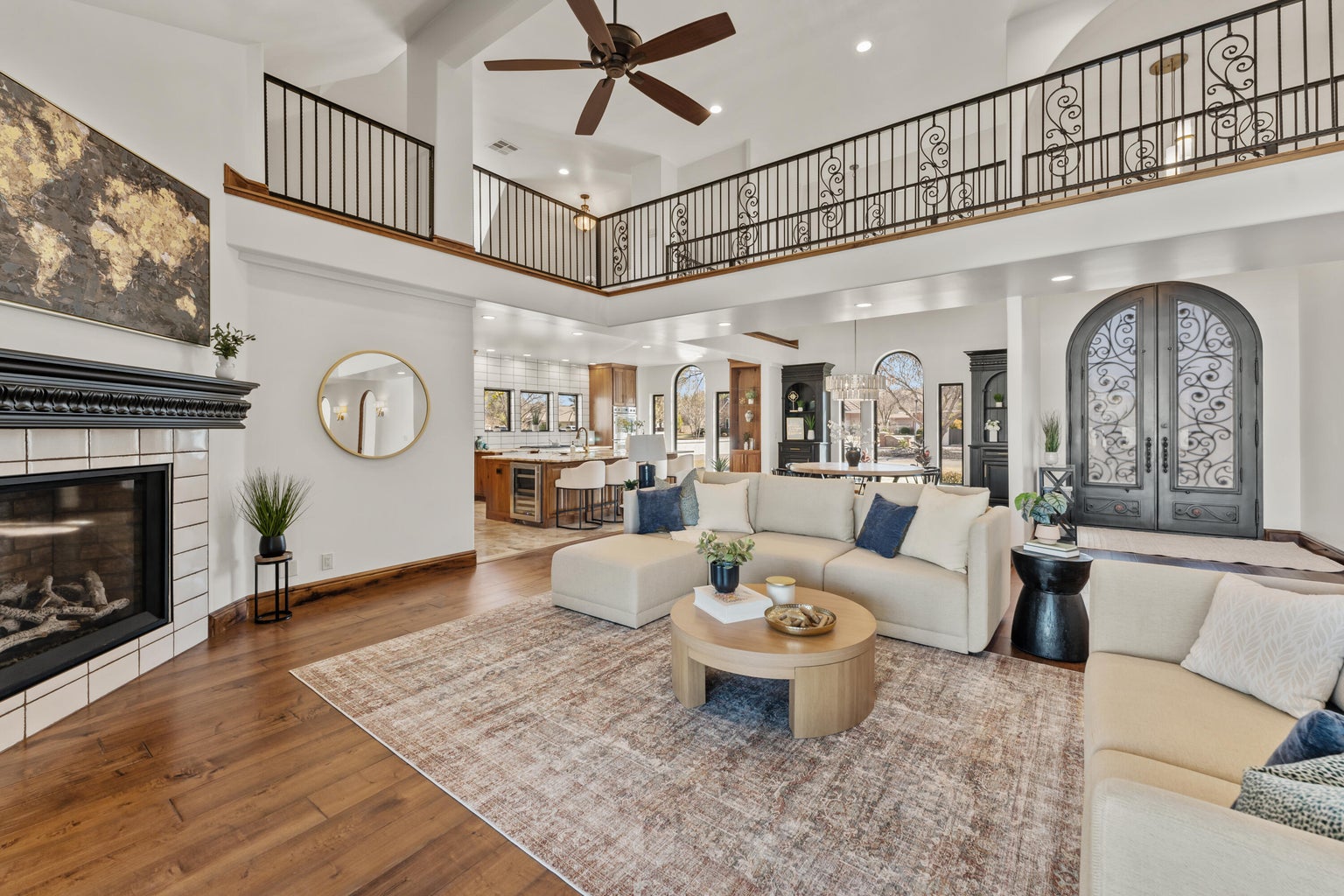 Living room featuring a glass covered fireplace, wood-type flooring, a ceiling fan, french doors, and arched walkways