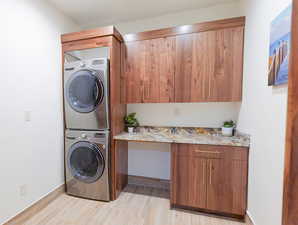 Main Laundry area with stacked washer and dryer, wood finish floors, and cabinet space