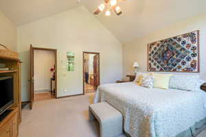 Bedroom featuring light colored carpet, lofted ceiling, a ceiling fan, and ensuite bathroom