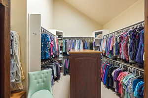Walk in closet with vaulted ceiling and light carpet