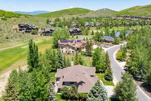 Aerial view of residential area featuring a mountainous background and a golf club