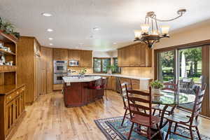 Dining space with light wood-style flooring, hanging lights, and a textured ceiling