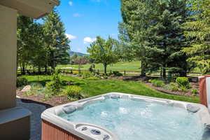 View of yard with a hot tub, a mountain view, golf course view, and a patio