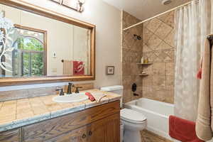Full bath featuring vanity, shower / bath combination with curtain, and a textured ceiling