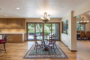 Dining room with suspended lighting, a textured ceiling, and light wood-style flooring