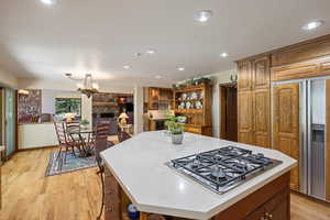 Kitchen with wood finish cabinets, a center island, light wood-style flooring, and stainless steel gas cooktop