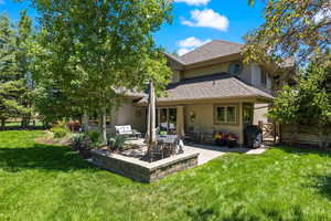 Back of house featuring a patio, a yard, stucco siding, and roof with shingles