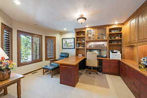 Home office featuring recessed lighting, light colored carpet, built in desk, and a textured ceiling