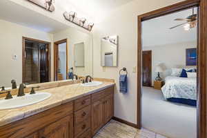 Full bath with double vanity, ceiling fan, light carpet, ensuite bathroom, and a bath