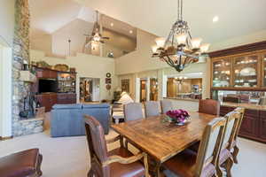 Dining area with ceiling fan, light carpet, suspended lighting, and vaulted ceiling