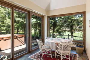 Sunroom / solarium with stone tile flooring, a jacuzzi, healthy amount of natural light, and vaulted ceiling