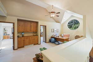 Interior space with lofted ceiling, a ceiling fan, light carpet, and an office area