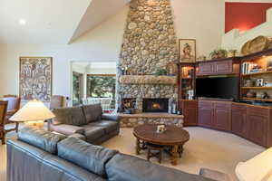 Living room with light colored carpet, a fireplace, and vaulted ceiling