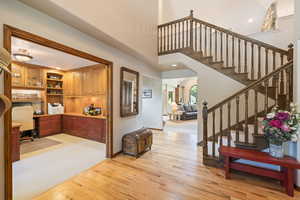 Foyer with built in desk, light wood-style flooring, a high ceiling, and recessed lighting