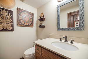 Bathroom with vanity, a textured ceiling, and a textured wall
