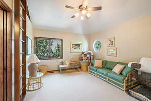 Living area featuring carpet, ceiling fan, and vaulted ceiling
