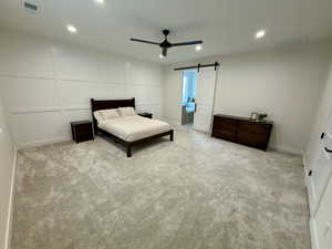 Bedroom featuring a barn door, a decorative wall, recessed lighting, light carpet, and ceiling fan