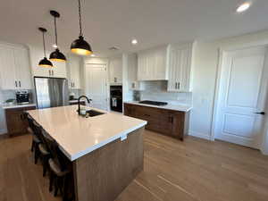 Two tone kitchen with two tone cabinetry, a breakfast bar, tasteful backsplash, and dark wood-style flooring