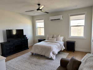 Bedroom featuring a wall mounted mini split, light wood finished floors, and a ceiling fan