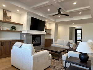 Living area featuring coffered ceiling, recessed lighting, a premium fireplace, ceiling fan, and light wood finished floors