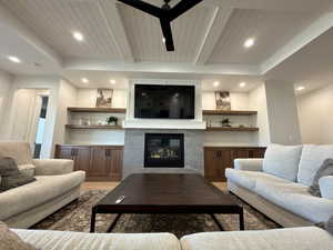 Living area featuring a high end fireplace, light wood-style flooring, recessed lighting, a wooden ceiling with exposed beams, and a ceiling fan