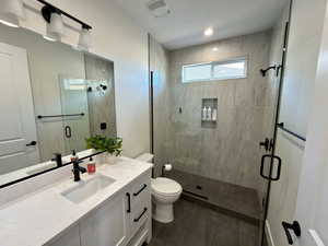 Full bathroom with a stall shower, vanity, and dark tile patterned floors