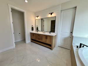 Bathroom featuring double vanity, light marble finish flooring, a garden tub, and recessed lighting
