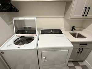 Laundry area with tile patterned floors, cabinet space, and independent washer and dryer