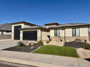 Prairie-style home featuring stucco siding, stone siding, driveway, and an attached garage