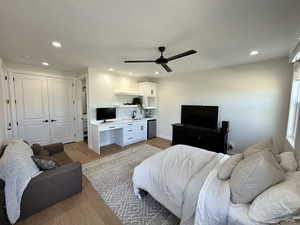 Bedroom with light wood-type flooring, a closet, ceiling fan, an office area, and stainless steel fridge