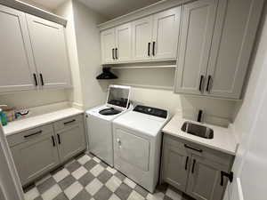 Laundry area featuring light flooring, cabinet space, and washing machine and dryer
