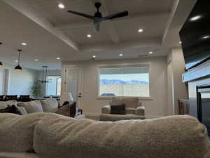 Living area with a ceiling fan, a glass covered fireplace, a wood ceiling with exposed beams, and a chandelier