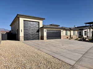 Prairie-style house with stone siding, an attached garage, driveway, and stucco siding