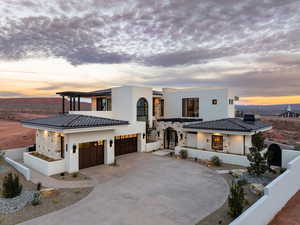 View of front of property with stone siding, driveway, stucco siding, a garage, and a tile roof