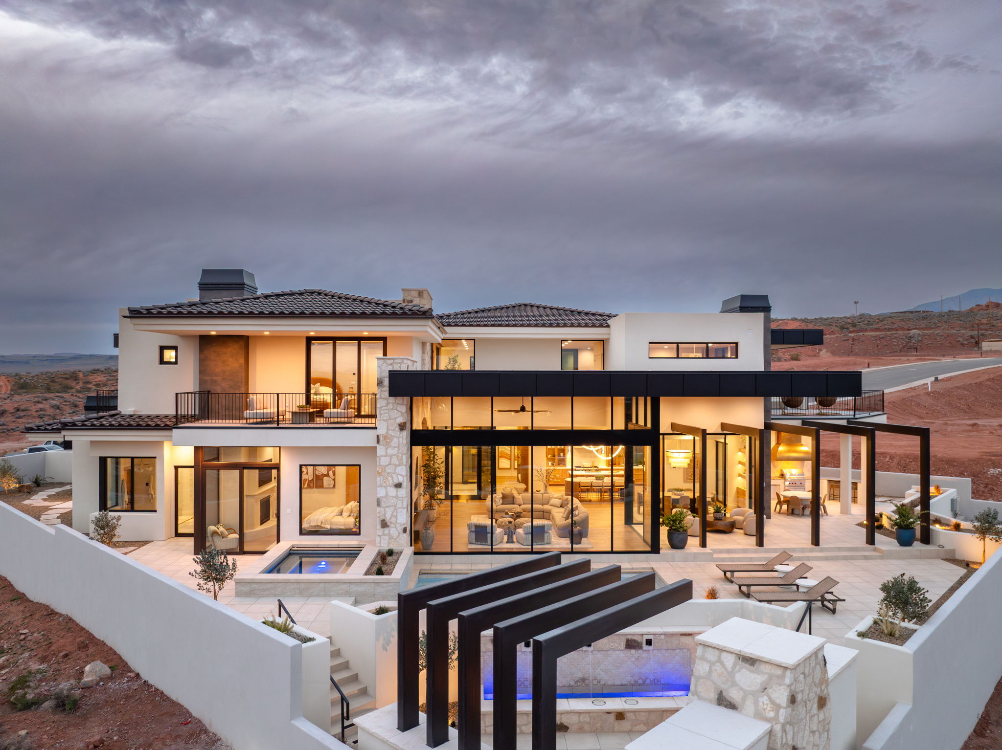 Rear view of property with a chimney, an in-ground hot tub, a tile roof, stucco siding, and a patio area