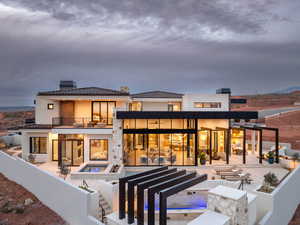 Rear view of property with a chimney, an in-ground hot tub, a tile roof, stucco siding, and a patio area