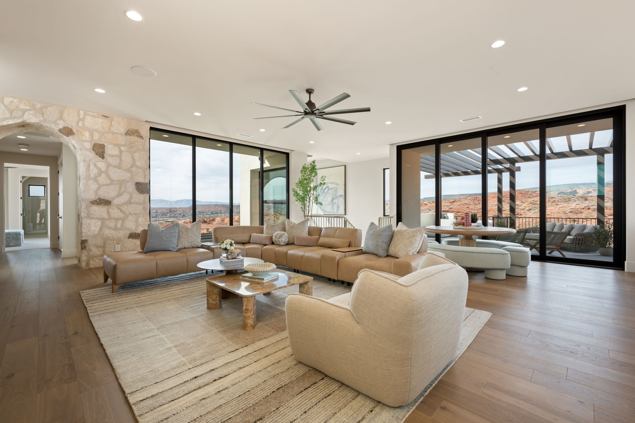 Living room with floor to ceiling windows, a mountain view, arched walkways, hardwood / wood-style floors, and a ceiling fan