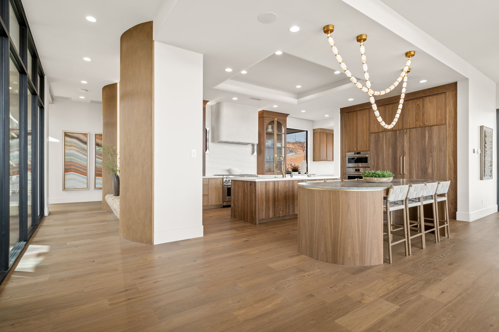 Kitchen with a kitchen bar, light wood-style floors, light stone countertops, stainless steel stove, and wood finish cabinetry