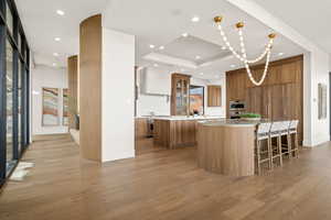 Kitchen with a kitchen bar, light wood-style floors, light stone countertops, stainless steel stove, and wood finish cabinetry