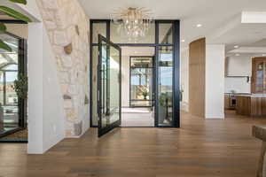 Foyer featuring expansive windows, dark wood-style floors, and a chandelier