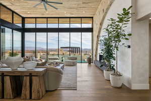 Living area with expansive windows, wooden ceiling, wood-type flooring, a ceiling fan, and a mountain view
