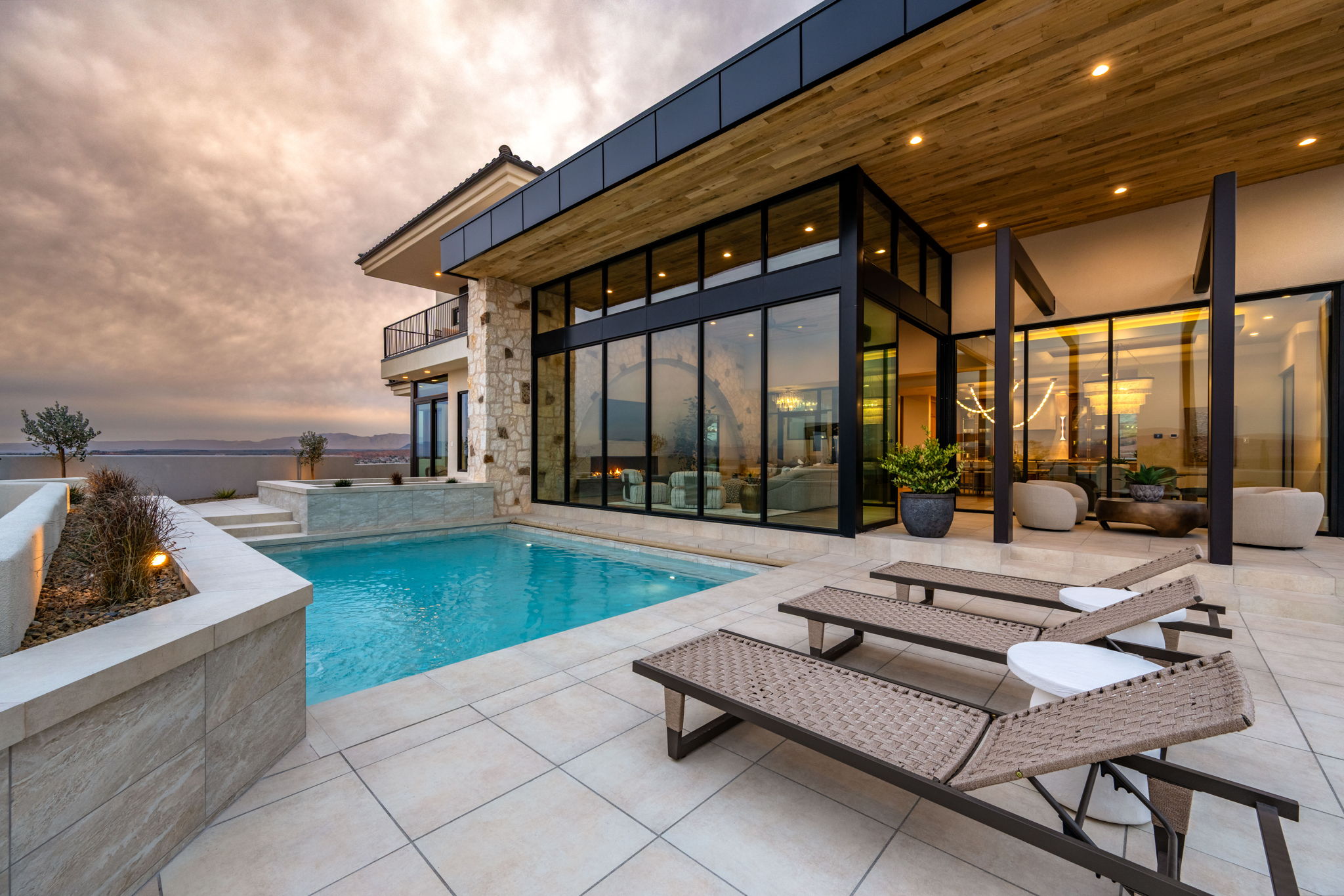 Pool at dusk featuring an outdoor pool, a balcony, and a patio area
