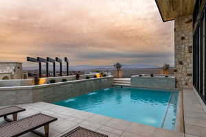 Pool at dusk featuring an in-ground hot tub and a mountain view