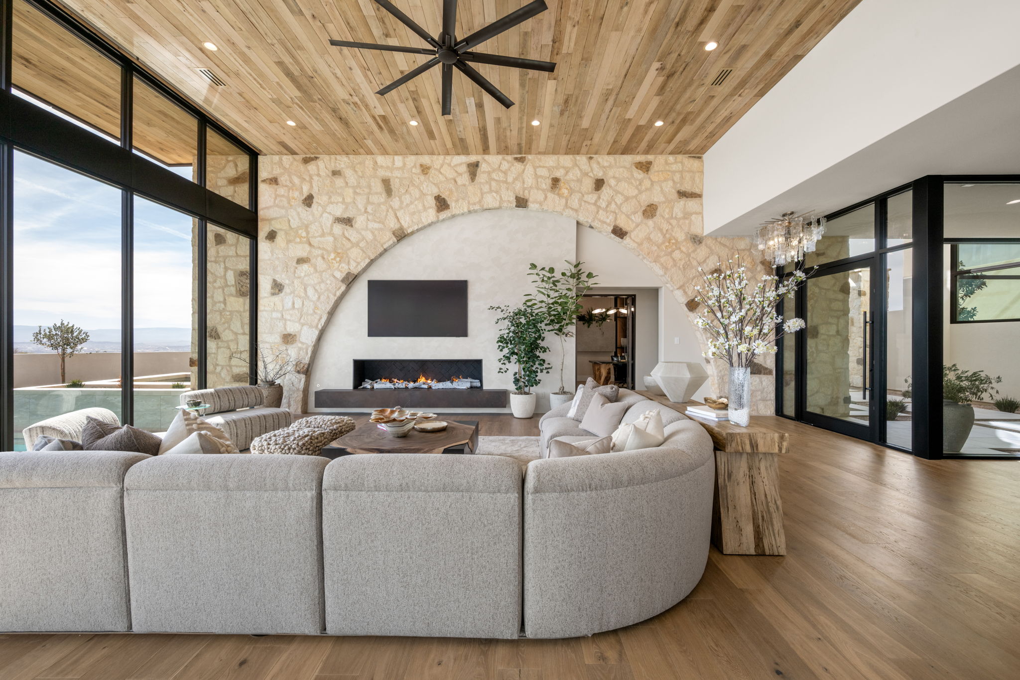 Living area with expansive windows, wood finished floors, ceiling fan, and wooden ceiling