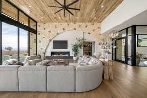 Living area with expansive windows, wood finished floors, ceiling fan, and wooden ceiling
