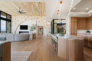 Kitchen featuring wood finish cabinets, open floor plan, a kitchen island, ceiling fan, and recessed lighting